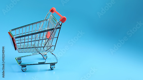 a miniature shopping cart, angled to the left, positioned against a solid blue background