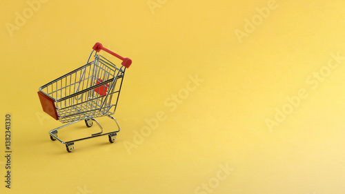 a miniature shopping cart in horizontal yellow background