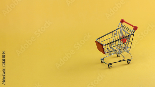 a miniature shopping cart in horizontal Yellow background