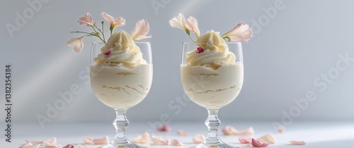 Two glasses of creamy dessert garnished with flower petals are shown