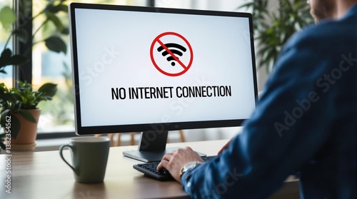 Man at desk with no internet connection message displayed on computer screen