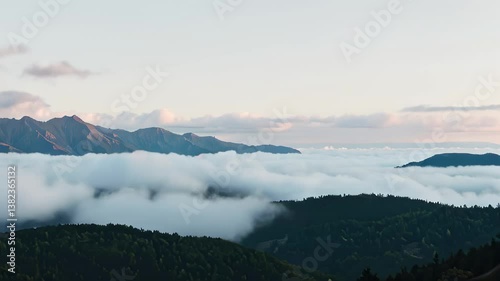 Serene mountain landscape enveloped in soft clouds at dawn  