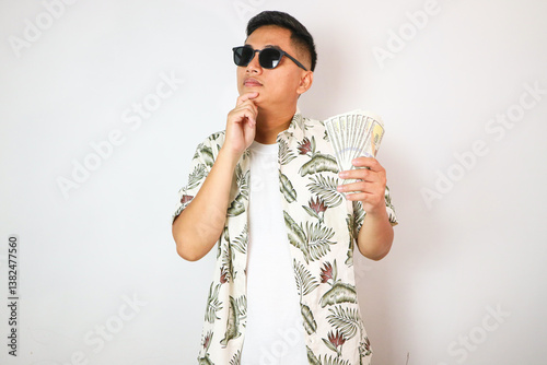 Asian man showing thinking expression when looking to US dollar money that he hold photo