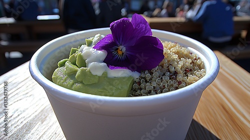 Colorful food bowl with avocado, quinoa, yogurt, & flower on wood