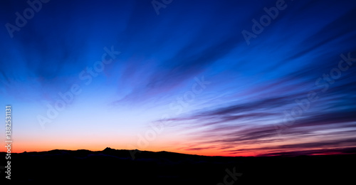 雄大で鮮やかな夜明けの空と山並みのシルエット。