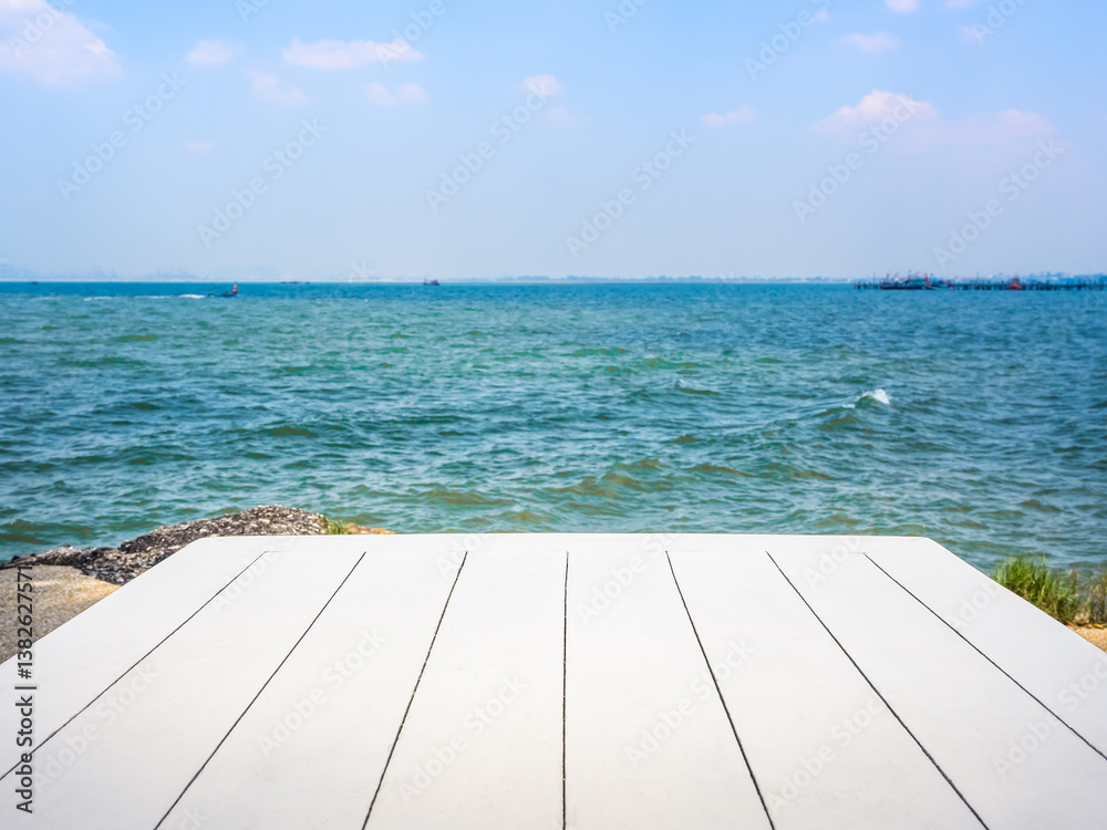 Fototapeta premium Summer vacation concept with seascape background for placed products. Empty white wood plank top table on tropical sea ocean scene on open blue sky and white clouds, horizontal abstract background.