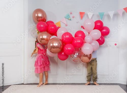 Obraz na płótnie Funny kids hide heads in butch of bday balloons, concept image w salonie