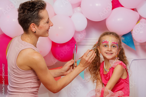 Obraz na płótnie A girl beams with joy as an adult woman applies unicorn makeup w salonie