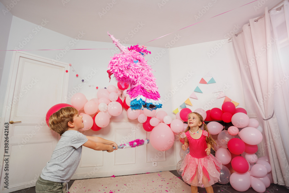 Dynamic image of small boy hitting unicorn pinata at bday party