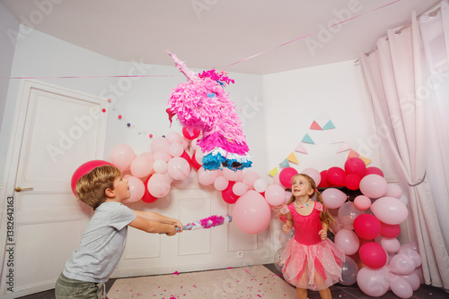 Obraz na płótnie Dynamic image of small boy hitting unicorn pinata at bday party w salonie