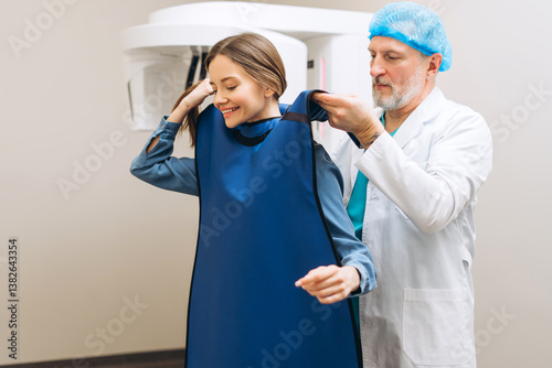 Male doctor helping for woman putting protective gown for x-ray procedure