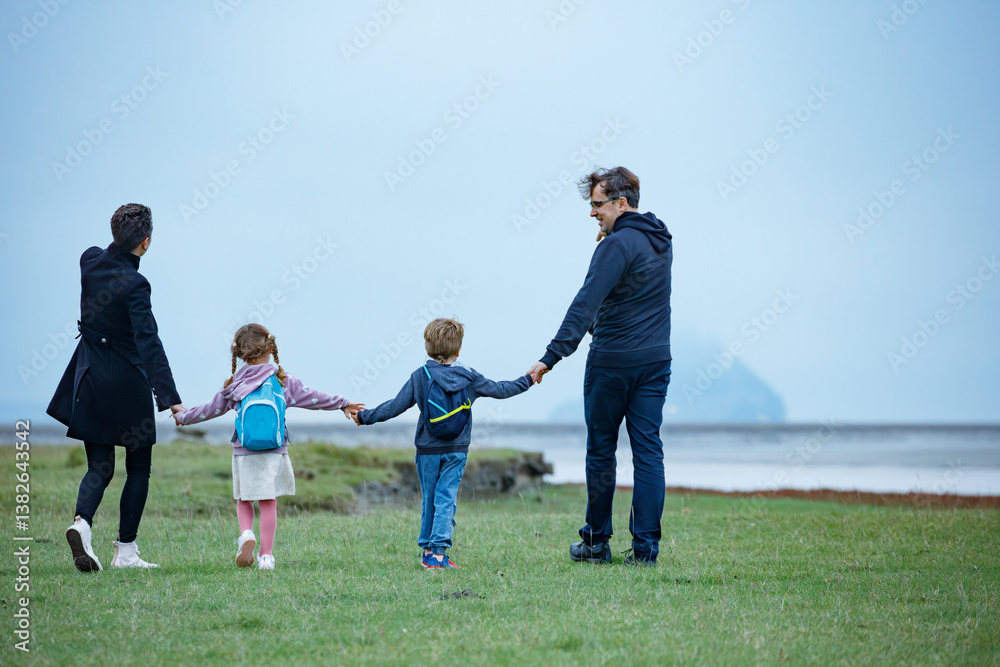 A family of four walk at field, foggy day in Normandy, France