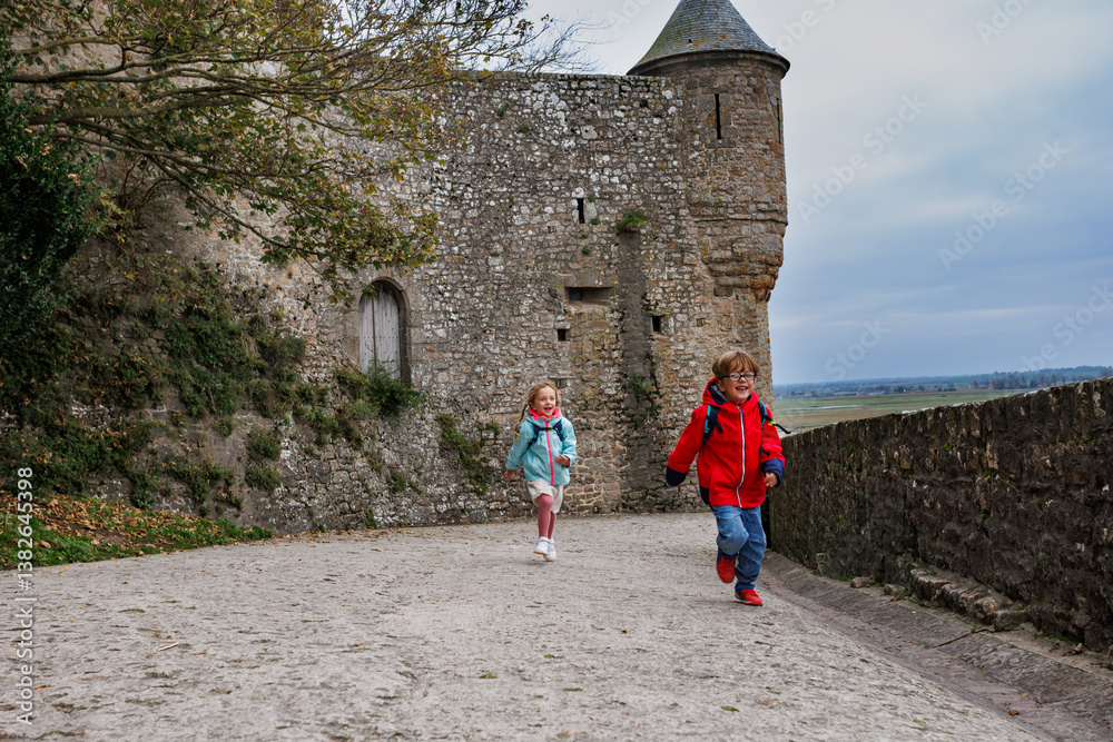 Children run on ancient stone walls of Mont Saint Michel, France