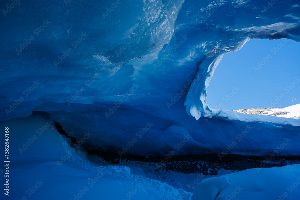 Blue ice cave with bright light seeping through ceiling opening