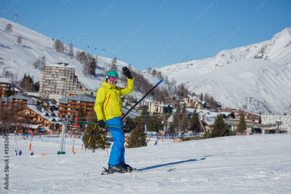 Skier man waving while enjoying sunny slopes at a ski resort