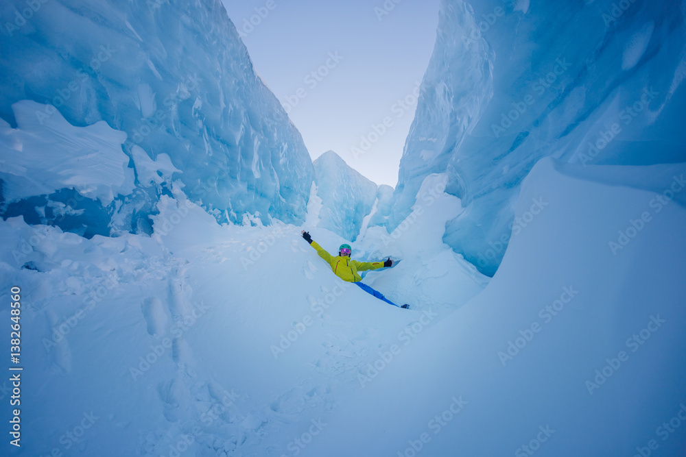 Ice explorer sitting in blue, snow-filled crevasse adventure