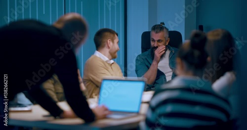 A diverse team of young professionals collaborates in a modern office conference room. Businesspeople discuss strategy, technology, and planning, using laptops to develop an innovative e-commerce