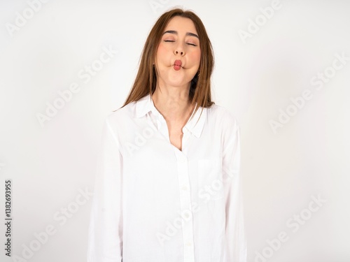 Caucasian young girl wearing white shirt   making fish face with lips, crazy and comical gesture. Funny expression.