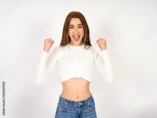 Caucasian young girl wearing white T-shirt  celebrating surprised and amazed for success with arms raised and open eyes. Winner concept.