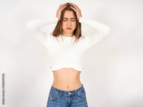 Caucasian young girl wearing white T-shirt suffering from strong headache desperate and stressed because of overwork. Depression and pain concept.