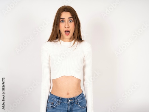 Oh my God. Surprised Caucasian young girl wearing white T-shirt stares at camera with shocked expression exclaims with unexpectedness,