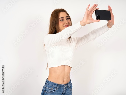 Caucasian young girl wearing white T-shirt  taking a selfie to post it on social media or having a video call with friends.