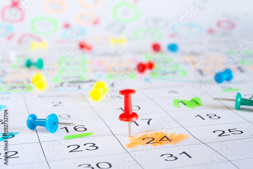 Calendar with business appointments and pushpins or thumbtacks, selective focus. Business concept,beat the clock,overworked, red tape.
