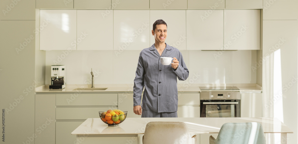 Smiling young man in pajamas standing in a kitchen Smiling young man in pajamas standing in a kitchen