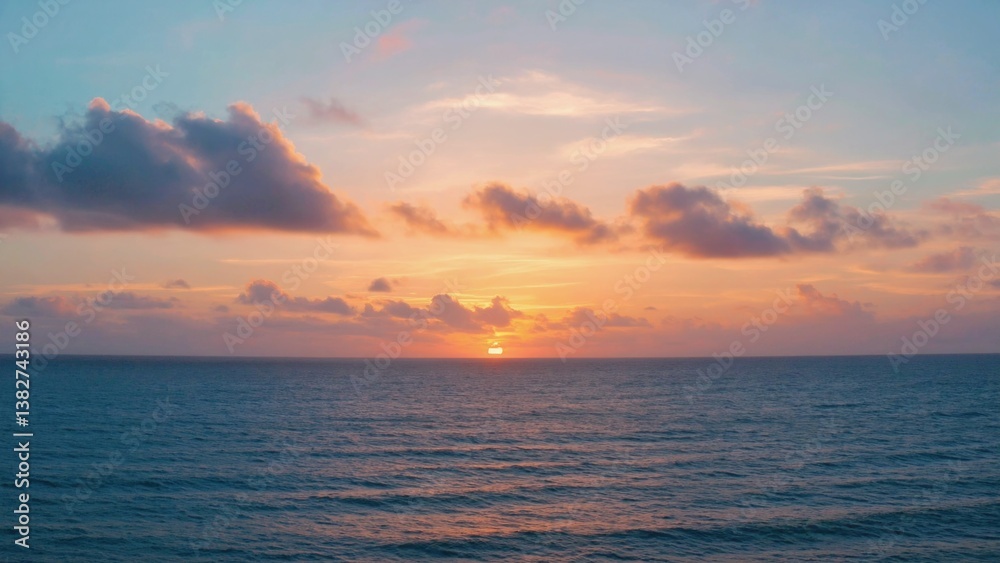 Fototapeta premium Glowing sunset over calm ocean with scattered clouds.