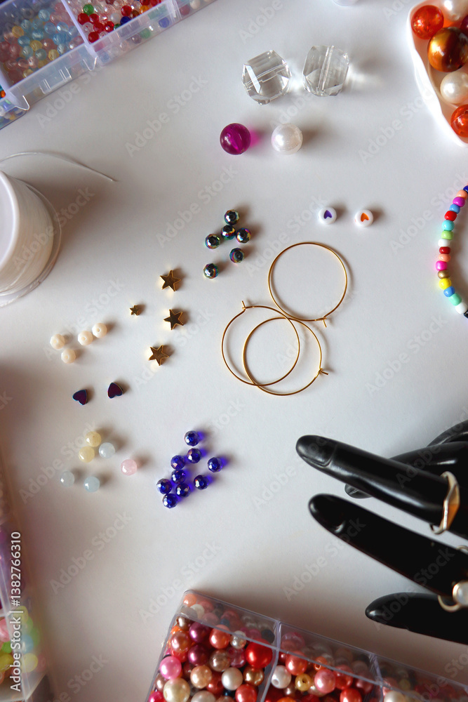 Hand figurine, colorful friendship bracelets, necklaces, various beads and DIY supplies on the table. Making jewelry at home. Flat lay.