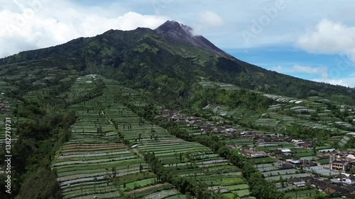 Rural villages near massive smoking volcano of Merapi, aerial view with rice terrace 