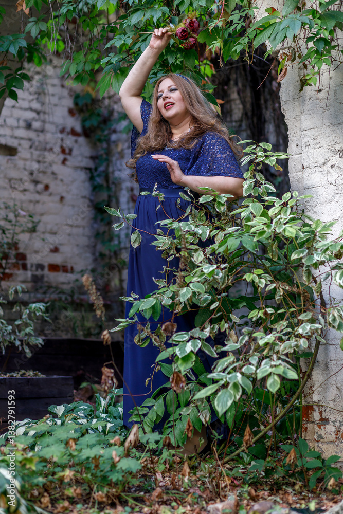 Woman in a long blue dress in the garden.