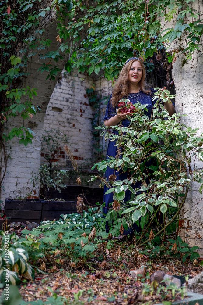 Woman in a long blue dress in the garden.