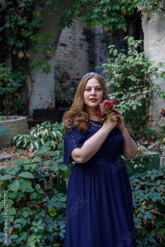 Woman in a long blue dress in the garden.