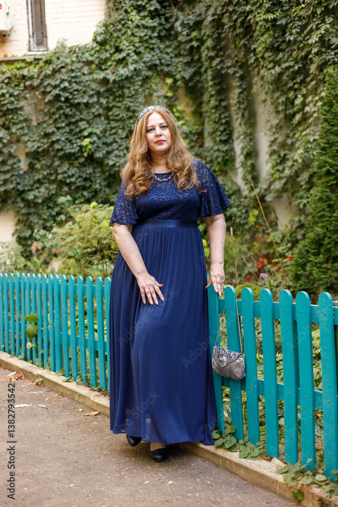 Woman in a long blue dress in the garden.