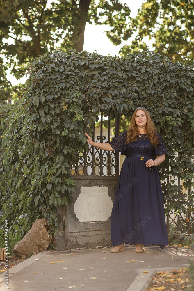 Woman in a long blue dress in the garden.
