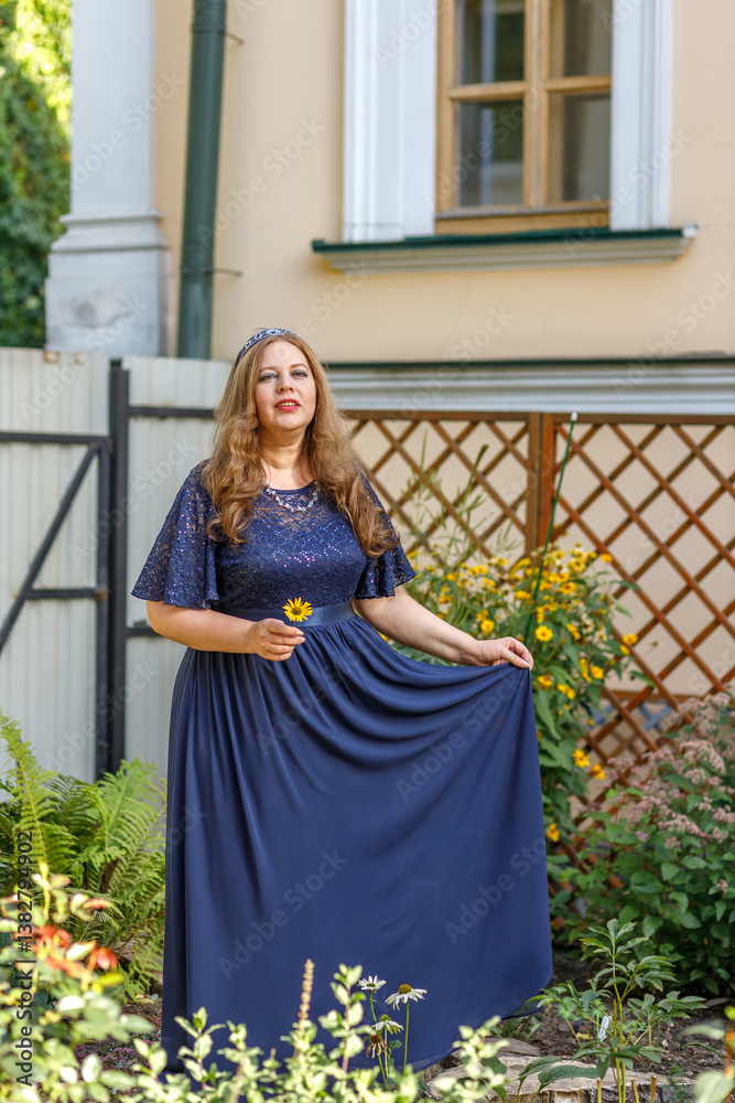 Woman in a long blue dress in the garden.