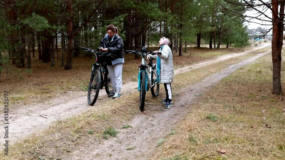 Two cyclists take a break along a dirt path in a forest during a cool autumn day Two cyclists take a break along a dirt path in a forest during a cool autumn day