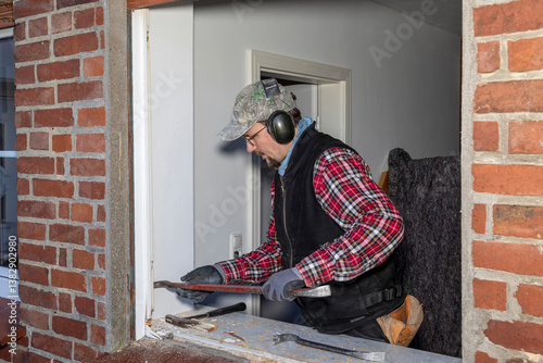 Photos Construction worker dismantling old window frame in brick house.