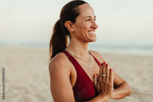 Smiling woman meditating on a serene beach during a calm sunset