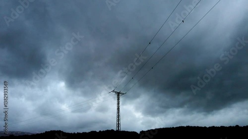 Ominous clouds moving above power lines and forest