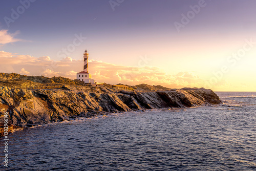 Obraz na płótnie Faro de Favaritx Golden Hour. Menorca Striking Lighthouse Amidst a Sunset Glow. A breathtaking sunset over the iconic lighthouse and its rocky surroundings w salonie