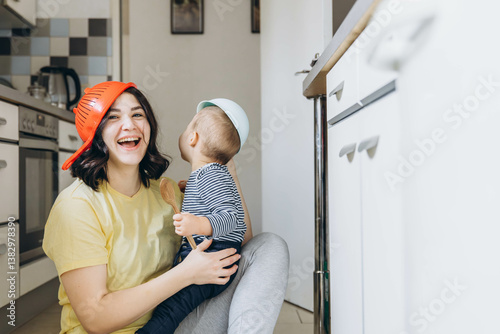 Mother and baby playing with pots and pans in the kitchen, goofing around and having fun