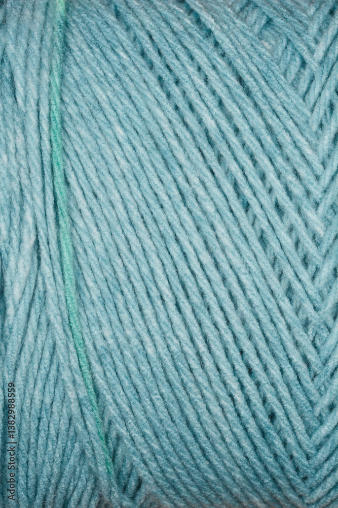 Fototapeta premium A close-up texture shot of blue yarn with diagonal stripes and a prominent green thread