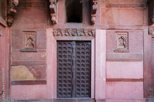 
An old metal door of the 16th Century red sandstone Red Fort, with pretty carved crowning, niches and architectural details, Agra, Uttar Pradesh, India