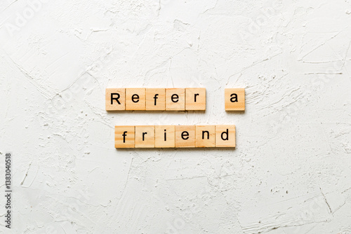 refer a friend word written on wood block. refer a friend text on table, concept