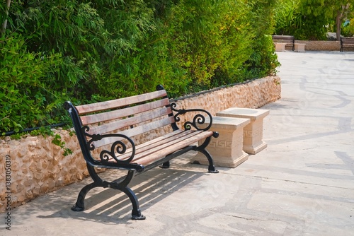 Weathered vintage wooden park bench, outdoor wood seat with forged curly metal legs and armrests. City outdoor furniture