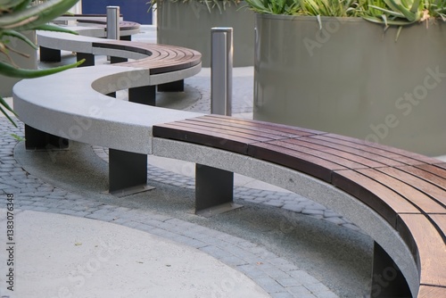Recreation area with empty creative contemporary curved long wooden and stone polished snake shaped bench .Urban modern public vandal proof furniture. Public city space resting area design