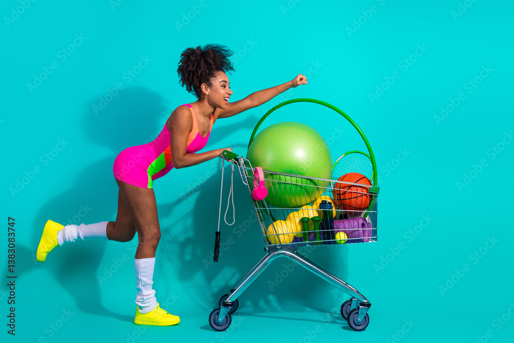 Fototapeta premium Young woman pushing a cart filled with fitness gear in vibrant and colorful sportswear, expressing a dynamic and active lifestyle.