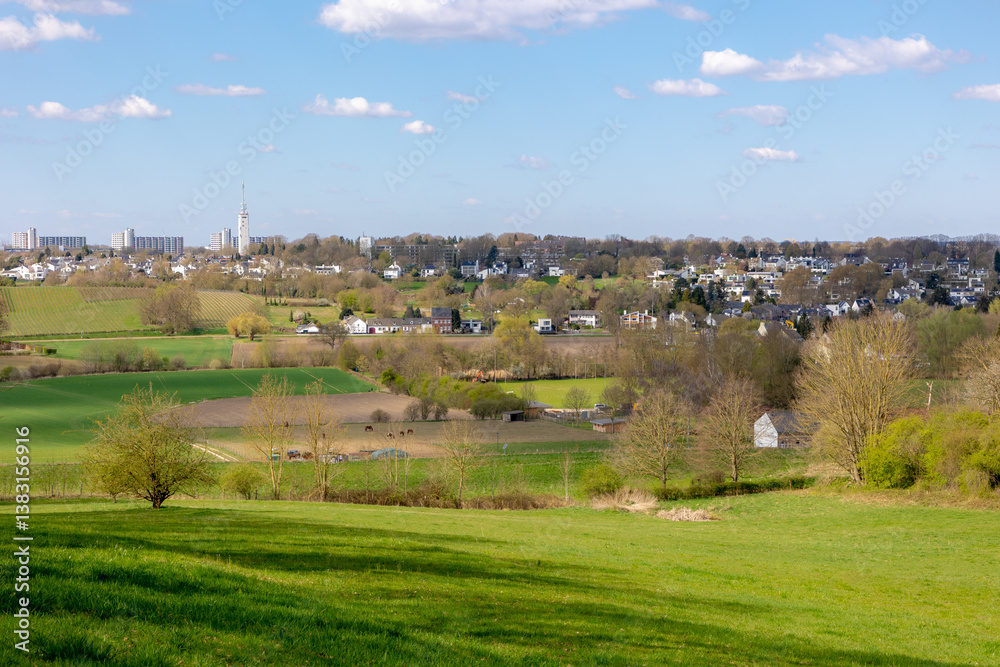 Overview of Maastricht, Terrain of hilly countryside green grass meadow and farmland, Combination with old and new modern buildings, Houses and church on hillside with blue sky, Limburg, Netherlands. Overview of Maastricht, Terrain of hilly countryside green grass meadow and farmland, Combination with old and new modern buildings, Houses and church on hillside with blue sky, Limburg, Netherlands.